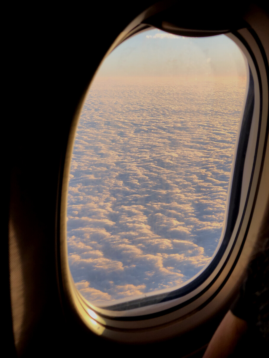 Fluffy clouds though airplane window during flight